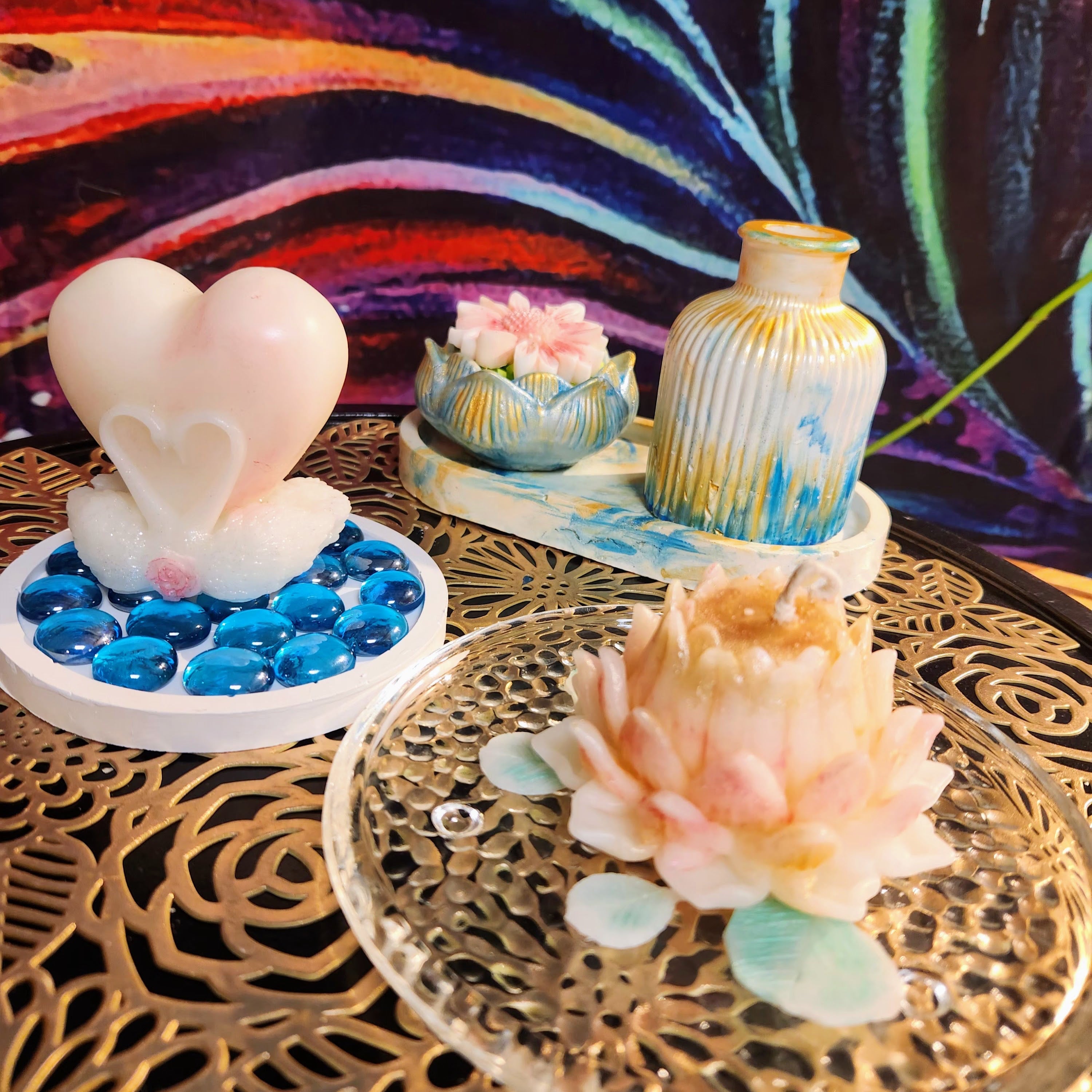 Decorative items including a heart-shaped object, a vase, and a flower on a decorative table with a colorful background.
